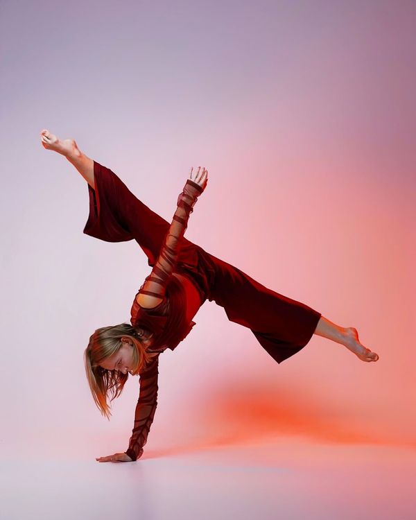 Woman in a dynamic yoga flow pose in a dark studio with yellow light.